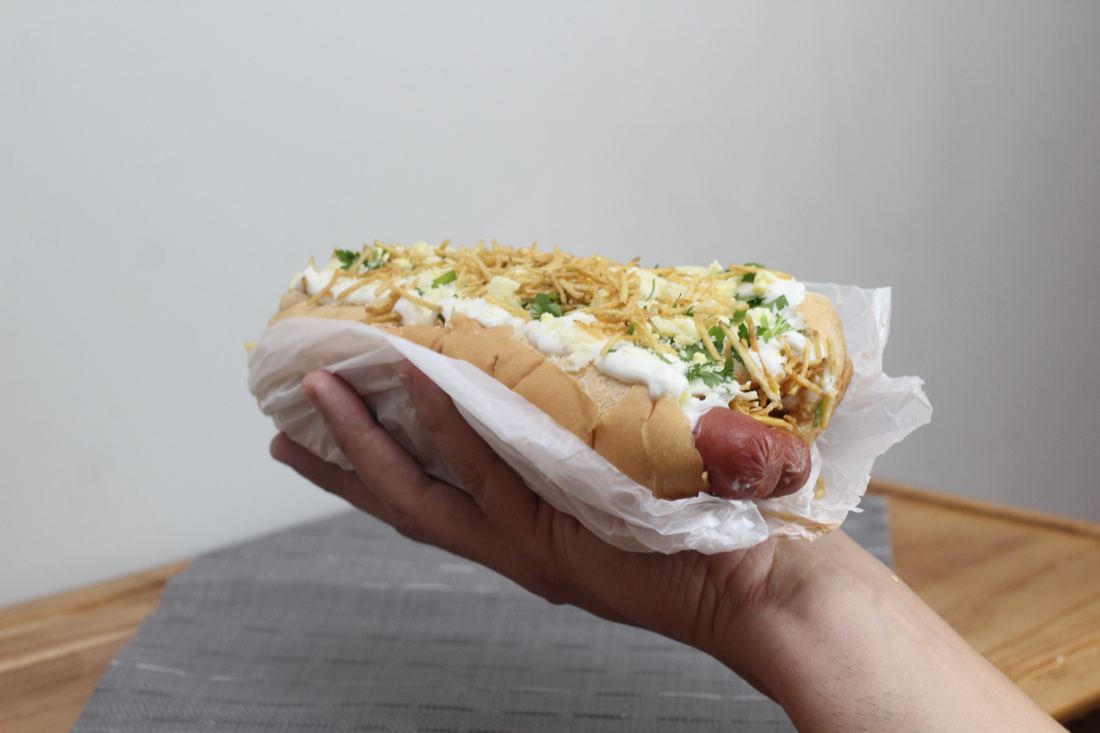 Cachorro-quente aberto na mão, pronto para comer